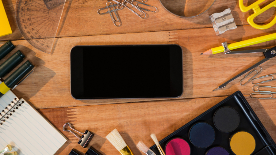 Close-up of mobile phone with various stationery on a table